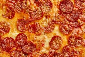 Closeup of pepperoni slices covered with melted mozzarella on baked pizza photo