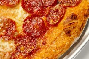 Closeup of pepperoni pizza slice with sausage, tomato sauce and melted mozzarella photo