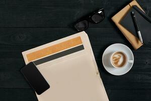 Smart phone with black display on wooden background. Newspaper and coffee on wooden table. Top view. photo