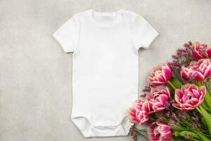 blanco bebé niña o chico traje Bosquejo plano laico con tulipán flores en gris hormigón antecedentes. diseño mono plantilla, impresión presentación burlarse de arriba. parte superior vista. foto