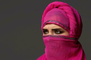 Close-up shot of a young charming woman wearing the pink hijab decorated with sequins. Arabic style. photo