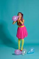 encantador niña con un multicolor trenzas peinado y brillante constituir, posando en estudio con aire globos en contra un azul antecedentes. foto