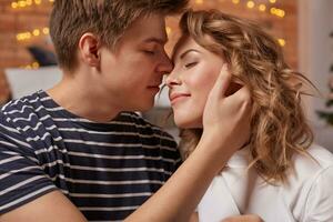 Close up portrait of a beautiful couple sitting on the floor embracing and looking to each other photo