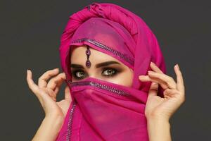 Close-up shot of a young charming woman wearing the pink hijab decorated with sequins and jewelry. Arabic style. photo