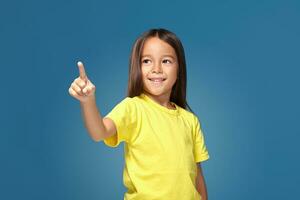 Cute girl shows finger on blue background photo