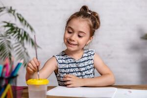 Inspired little girl at the table draw with paints photo