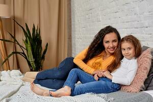 Love of young mother and daughter. They lie on the bed at home and have fun photo