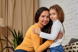 Love of young mother and daughter. They sit on the bed at home and have fun photo