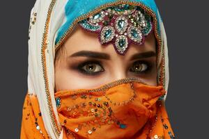 Studio shot of a chrming female wearing the colorful hijab decorated with sequins and jewelry. Arabic style. photo