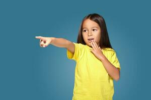 Cute girl shows finger on blue background photo