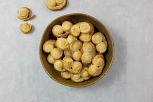 Puff pastry eyelet, Palmier cookies in a bowl with cinnamon and sugar on the light concrete background. Top view. photo