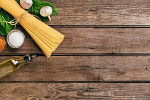 Pasta and ingredients on wooden background with copy space. Top view. Vegetarian food, healthy or cooking concept. photo