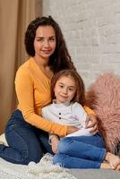 amor de joven madre y hija. ellos sentar en el cama a hogar y tener divertido foto