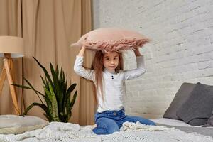 Portrait of adorable emotional little girl on the bed, with pillow photo