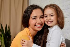 Love of young mother and daughter. They sit on the bed at home and have fun photo