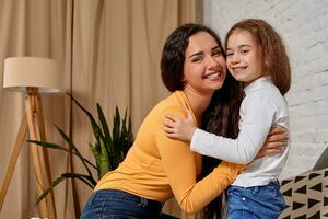 Love of young mother and daughter. They sit on the bed at home and have fun photo