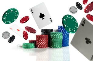 Multicolored chips in piles are standing on a surface, some of them are flying apart with playing cards, aces. Isolated on white background. photo