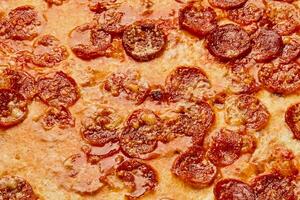 Closeup of caramelized cheese crust on pepperoni pizza with sausage and tomato sauce photo