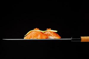 Nigiri sushi with raw salmon, avocado and red caviar on blade of Japanese knife photo