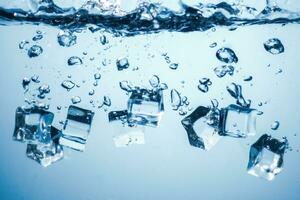 ice cubes falling down. ice cubes on blue background. splash on blue. ice cubes in water photo