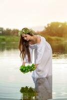 Woman in white dress in the water. Art Woman with wreath on her head in river. Wreath on her head, Slavic traditions and paganism photo