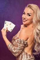 Blonde woman with a perfect hairstyle and bright make-up is posing with playing cards in her hands. Casino, poker. photo