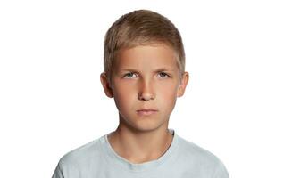 Close-up portrait of a blonde teenage boy in a white t-shirt posing isolated on white studio background. Concept of sincere emotions. photo