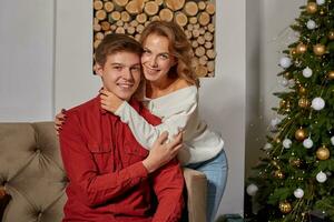 Happy young lovely couple on living room sitting on the couch near christmass tree photo