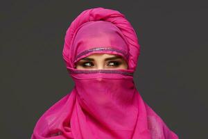 Close-up shot of a young charming woman wearing the pink hijab decorated with sequins. Arabic style. photo