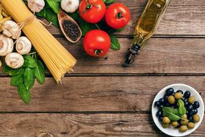 Pasta and ingredients on wooden background with copy space. Top view. Vegetarian food, healthy or cooking concept. photo