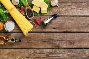 Pasta and ingredients on wooden background with copy space. Top view. Vegetarian food, healthy or cooking concept. photo