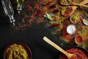 Assorted spices on dark black background. Seasonings for food. Curry, paprika, pepper, cardamom, turmeric. Top view. photo