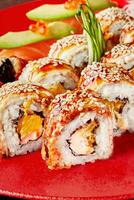 Sushi rolls with eel, cream cheese and orange topped with unagi sauce and sesame photo