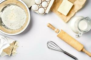 Preparation of the dough. A measurement of the amount of ingredients in the recipe. Ingredients for the dough flour, eggs, rolling pin, whisk, milk, butter, cream. Top view, space for text photo