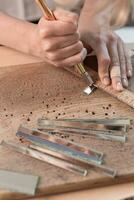 Artist cutting sheets of stained glass into small mosaic squares. Close-up photo