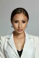 Close up portrait of a brunette model girl with professional evening make-up, wearing a white jacket with black bra, posing on gray background. photo