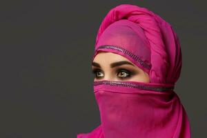 Close-up shot of a young charming woman wearing the pink hijab decorated with sequins. Arabic style. photo