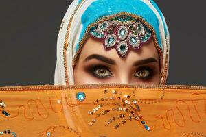 Studio shot of a chrming female wearing the colorful hijab decorated with sequins and jewelry. Arabic style. photo