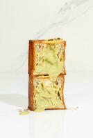 Two halves of flaky sweet cube croissant with pistachio custard and nut crumbs photo