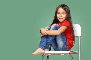 little girl wearing red t-short and posing on chair photo