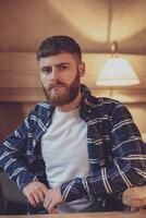 Portrait handsome bearded man wearing plaid shirt at modern cafe photo
