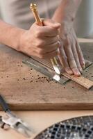 Artist cutting sheets of stained glass into small mosaic squares. Close-up photo