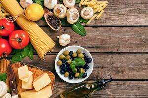 Ingredients for spaghetti with basil, tomatoes, cheese on wooden background, top view, place for text photo