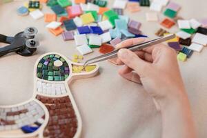 Hands of master working on new modern colorful mosaic. Close-up photo