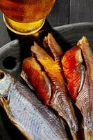 Closeup of whole and skinned salted air-dried roach with roe served with beer on black background photo