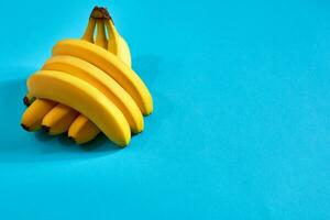 Fresh bananas close up on bright blue background. Flat lay. Summer concept. photo