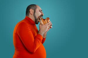 de cerca retrato de un de edad mediana hombre con barba, vestido en un rojo suéter tipo con cuello de tortuga, posando con hamburguesas en contra un azul antecedentes. rápido alimento. foto