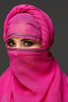 Close-up shot of a young charming woman wearing the pink hijab decorated with sequins. Arabic style. photo