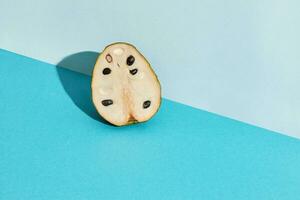 Close up high quality image of half of sugar-apple, fruit of Annona squamosa cherimoya, fruit composition on blue pastel photo