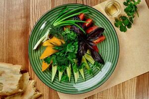 Assorted sliced vegetables with fresh greens on platter with shotis puri and chacha photo